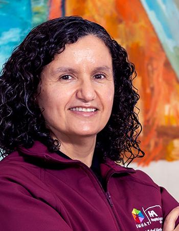 Es la foto de perfil de una médica internista y especialista en medicina crítica en Tijuana de Hospital Angeles. Usa una camisa color vino. Tiene el cabello corto y negro. Está sonriendo.