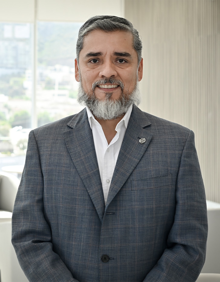 Es la foto de perfil de un nefrólogo en San Pedro Garza de Hospital Angeles Valle Oriente. Usa un saco gris con una camisa blanca. Tiene el cabello y la barba gris. Esta sonriendo y tiene cruzadas sus manos.