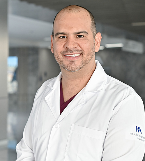 Es la foto de perfil de un ginecólogo y obstetra en Querétaro de Hospital Angeles Centro Sur. El doctor es calvo tiene una camisa de color gris y está sonriendo.