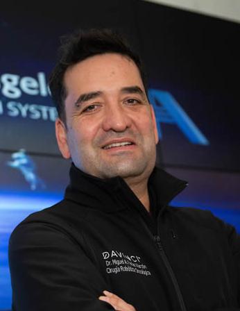 Es la foto de perfil de un cirujano oncológico en Ciudad de México de Hospital Angeles Universidad. Usa una chamarra negra. Tiene el cabello negro y los brazos cruzados. está sonriendo.