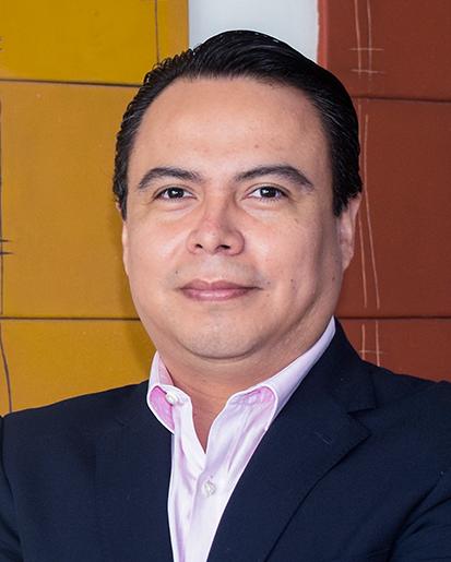 Es la foto de perfil de un neurólogo pediátrico en Xalapa de Hospital Angeles Xalapa. Usa un saco azul marino con una camisa rosa. Tiene el cabello negro. Está sonriendo ligeramente.