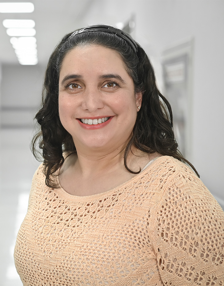 Es la foto de perfil de una pediatra y cirujana pediátrica en Ciudad de México de Hospital Angeles Universidad. Usa una blusa cafe tejida. Tiene el cabello negro, ondulado y corto. Está sonriendo.