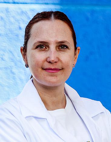 Es la foto de perfil de un nutriólogo en León de Hospital Angeles León. Utiliza una bata blanca, tiene los brazos cruzados, el fondo es azul fuerte.