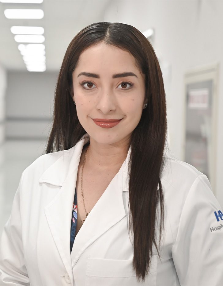 Es la foto de perfil de una ginecóloga y obstetra en Ciudad de México de Hospital Angeles Universidad. Usa una bata blanca. Tiene el cabello café, largo y lacio. Está sonriendo ligereramente.