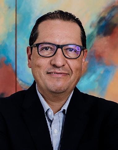 Es la foto de perfil de un urólogo en Tampico de Hospital Angeles Tampico. Usa un saco negro con una camisa azul claro. Tiene el cabello negro y usa lentes. Está sonriendo ligeramente.