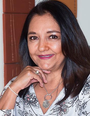 Es la foto de perfil de una nutrióloga especializada en necesidades médicas en Xalapa de Hospital Angeles Xalapa. Usa una blusa blanca con flores moradas y joyería plata. Tiene el cabello corto y negro. Está sonriendo.