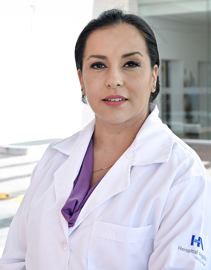 Es la foto de perfil de una oftalmóloga en León de Hospital Angeles León. Utiliza una bata blanca con una blusa azul marino, tiene labial rojo y el cabello recogido.