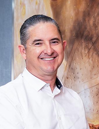 Es la foto de perfil de un cirujano neurológico en León de Hospital Angeles León. Utiliza una camisa blanca con cuello alto. El doctor está sonriendo y tiene cabello canoso.