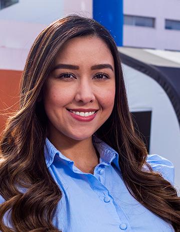 Es la foto de perfil de una pediatra en Tijuana de Hospital Angeles Tijuana. Usa una blusa azul claro. Tiene el cabello largo, ondulado y café. Está sonriendo.