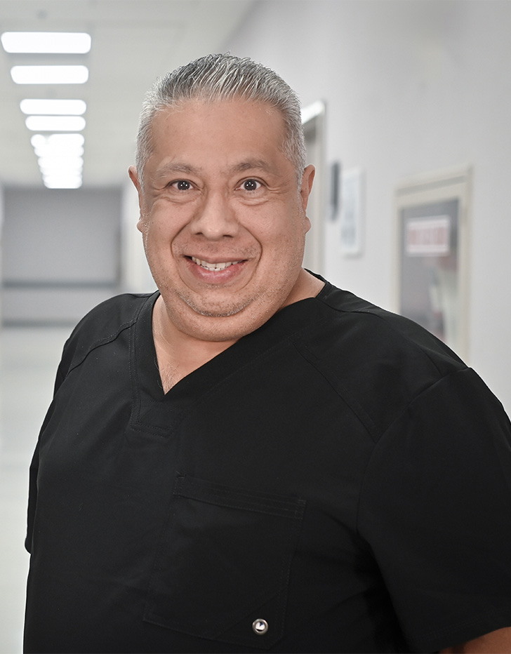 Es la foto de perfil de un cirujano oncológico en Ciudad de México de Hospital Angeles Universidad. Usa un uniforme médico negro. Tiene el cabello gris y está sonriendo.