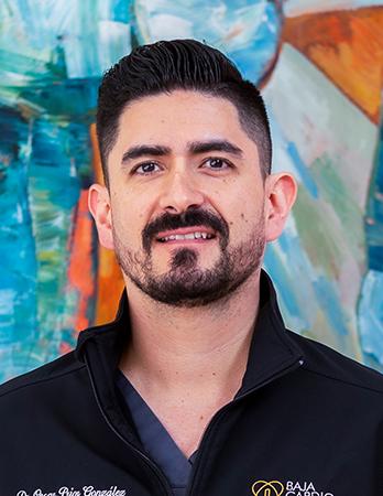 Es la foto de perfil de un cirujano cardiotorácico en Tijuana de Hospital Angeles Tijuana. Usa una chamarra negra. Tiene el cabello y barba negra. Está sonriendo ligeramente.