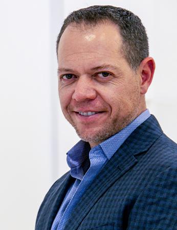 Es la foto de perfil de un urólogo en León de Hospital Angeles León. Utiliza un saco azul marino con cuadros y camisa azul cielo. 