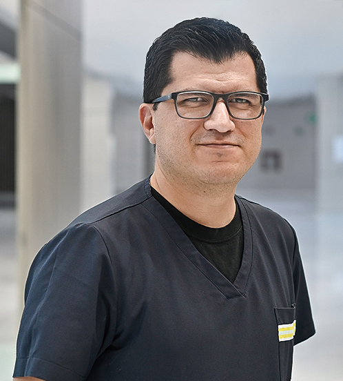 Es la foto de perfil de un ginecólogo y obstetra en Querétaro de Hospital Angeles Centro Sur. El doctor tiene un uniforme negro lentes cuadrados con Marco negro el doctor tiene un traje una camisa blanca y está sonriendo.