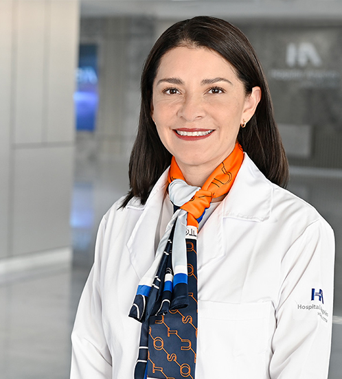 Es la foto de perfil de una gastroenteróloga pediátrica en Querétaro de Hospital Angeles Centro Sur. La doctora tiene una bata blanca una bufanda azul con líneas grises y cabello largo.