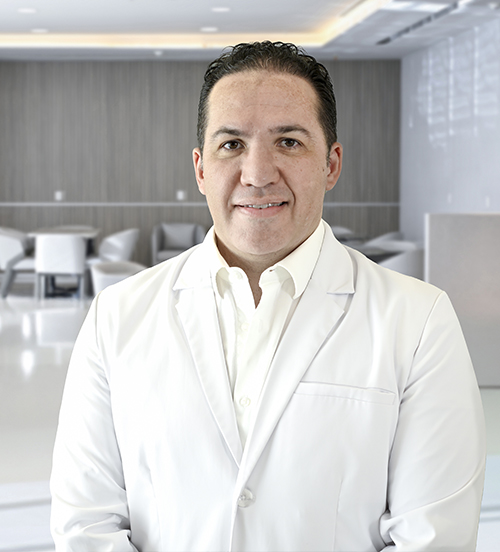 Es la foto de perfil de un alergólogo y especialista en inmunología y alergia pediátrica en San Pedro Garza de Hospital Angeles Valle Oriente. Usa un saco gris con una camisa blanca. Tiene un poco de cabello negro. Está sonriendo.