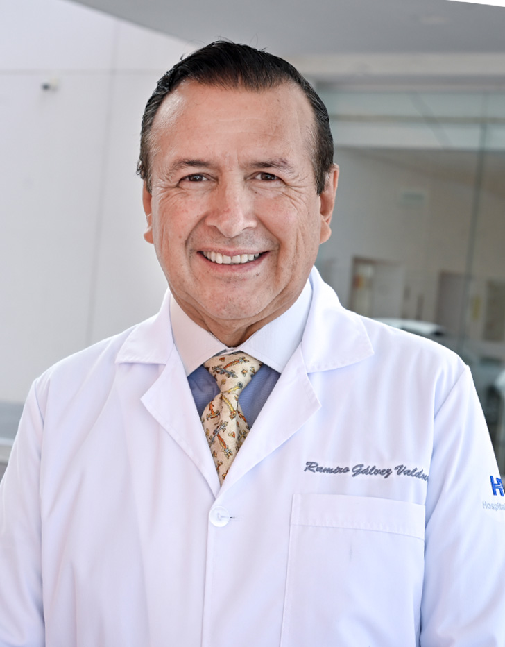 Es la foto de perfil de un cirujano general en León de Hospital Angeles León. Utiliza una bata blanca con una playera gris en cuello V.