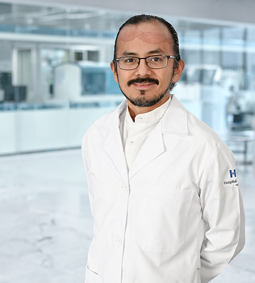 Es la foto de perfil de un cirujano neurológico en Guadalajara de Hospital Angeles Del Carmen. Tiene una bata blanca, corbata y camisa azul cielo.