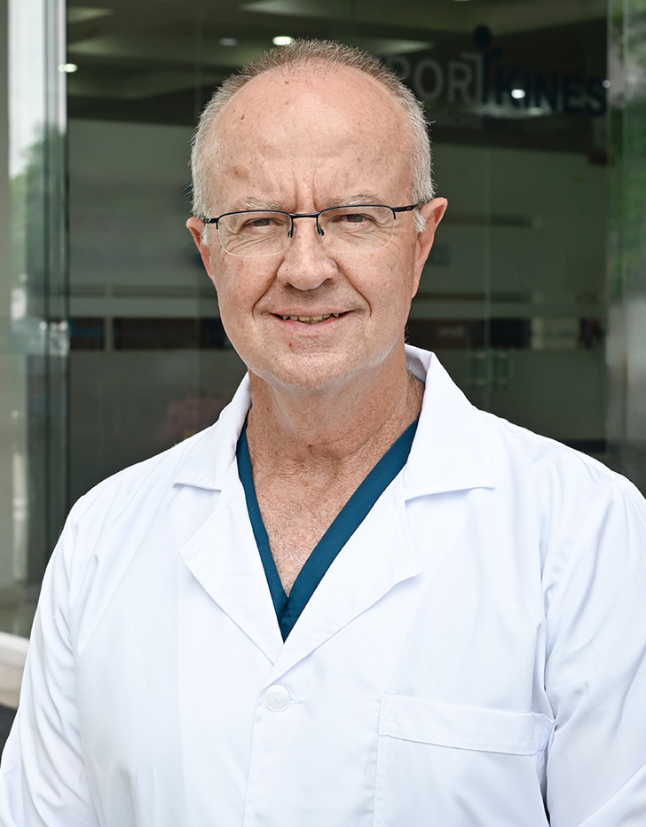 Es la foto de perfil de un gastroenterólogo, gastrocirujano y especialista en endoscopía en Villahermosa de Hospital Angeles Villahermosa. Usa una bata blanca con un uniforme médico azul. Es parcialmente calvo. Usa lentes y está sonriendo.