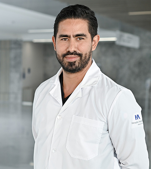 Es la foto de perfil de un urólogo en Querétaro de Hospital Angeles Centro Sur. Usa un uniforme azul marino , tiene barba y está sonriendo.
