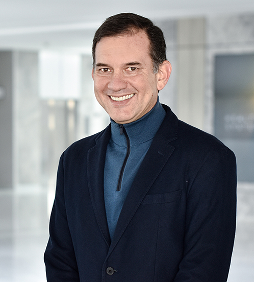 Es la foto de perfil de un ortopedista y traumatólogo pediátrico en Querétaro de Hospital Angeles Centro Sur. Usa un saco negro con una chamarra azul debajo, está sonriendo.