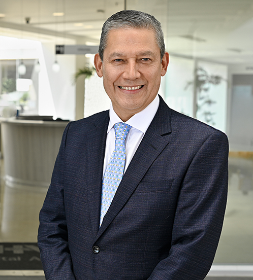 Es la foto de perfil de un ginecólogo y obstetra en Ciudad de México de Hospital Angeles Acoxpa. Usa un traje azul oscuro, una camisa blanca y una corbata azul con detalles azules y amarillos. Está sonriendo.