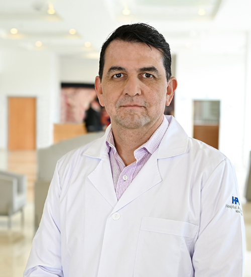 Es la foto de perfil de un especialista en ecocardiografía y cardiólogo en Xalapa de Hospital Angeles Xalapa. Usa una bata blanca con una camisa azul. Tiene el cabello negro. Tiene los brazos cruzados.