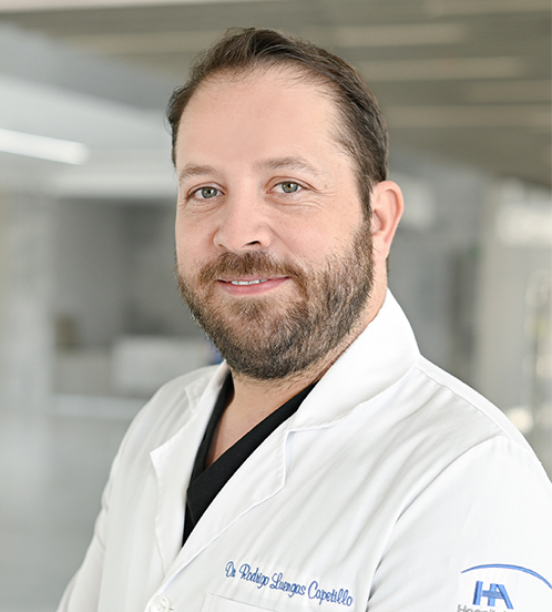 Es la foto de perfil de un otorrinolaringólogo en Querétaro de Hospital Angeles Centro Sur. Usa una bata blanca y una playera negra, tiene el cabello castaño claro y barba.