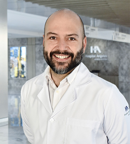 Es la foto de perfil de un cirujano neurológico en Querétaro de Hospital Angeles Centro-sur. Usa una bata blanca con una camisa beige claro. Es calvo y tiene barba color café claro.