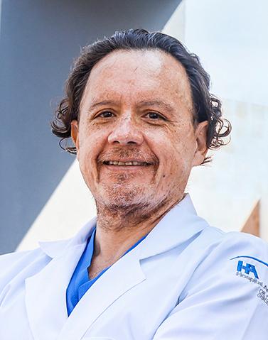 Es la foto de perfil de un urólogo en Guadalajara de Hospital Angeles Del Carmen. Utiliza una bata blanca, tiene el cabello rizado y ligeramente largo.