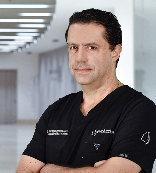 Es la foto de perfil de un cirujano plástico en Villahermosa de Hospital Angeles Villahermosa. Usa un uniforme médico negro. Tiene el cabello negro y los brazos cruzados. Está serio.