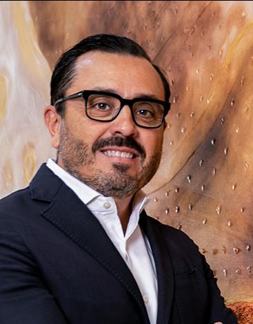 Es la foto de perfil de un cirujano general en León de Hospital Angeles León. Tiene cabello, barba y bigote color negro. Usa un saco negro, junto con una camisa blanca.