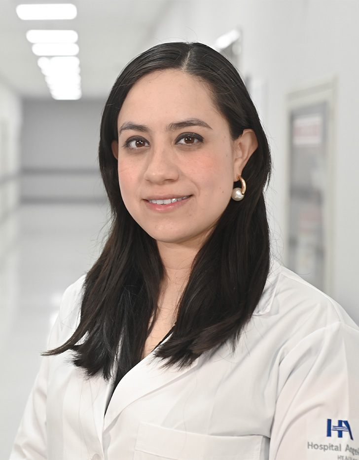 Es la foto de perfil de una neuróloga en Ciudad de México de Hospital Angeles Universidad. Usa una bata blanca. Tiene el cabello largo, lacio y negro. Está sonriendo y usa aretes plata.