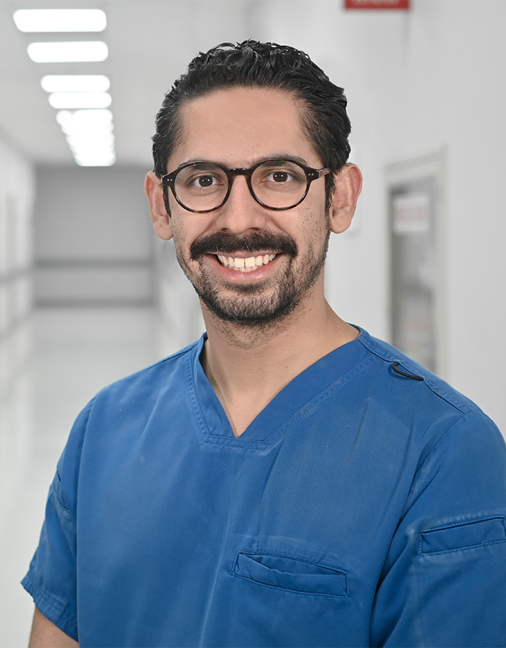 Es la foto de perfil de un neumólogo en Ciudad de México de Hospital Angeles Universidad. Usa un uniforme médico azul. Tiene el cabello y barba negra. Usa lentes. Está sonriendo.