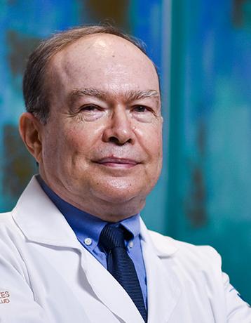 Es la foto de perfil de un especialista en alergología pediátrica y pediatra en Villahermosa de Hospital Angeles Villahermosa. Usa una bata blanca con una camisa y corbata azul. Tiene el cabello castaño. Está sonriendo ligeramente.