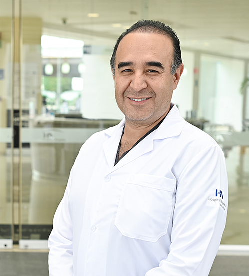 Es la foto de perfil de un ginecólogo y obstetra en Ciudad de México de Hospital Angeles Acoxpa. Usa una bata blanca con un uniforme médico negro. Tiene el cabello canoso y está sonriendo.