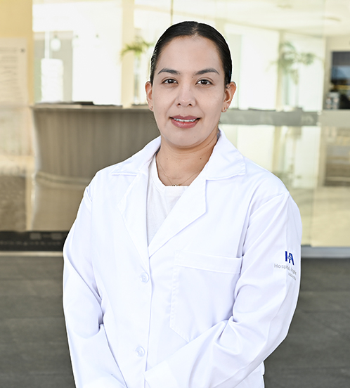 Es la foto de perfil de una radiooncóloga en Ciudad de México de Hospital Angeles Acoxpa. Usa una bata blanca con una blusa blanca. Tiene el cabello recogido y usa aretes dorados.