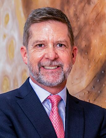 Es la foto de perfil de un gastroenterólogo pediátrico en León de Hospital Angeles León. Tiene el cabello castaño y una barba gris. Usa un saco color azul marino con una camisa azul claro y una corbata rosa.