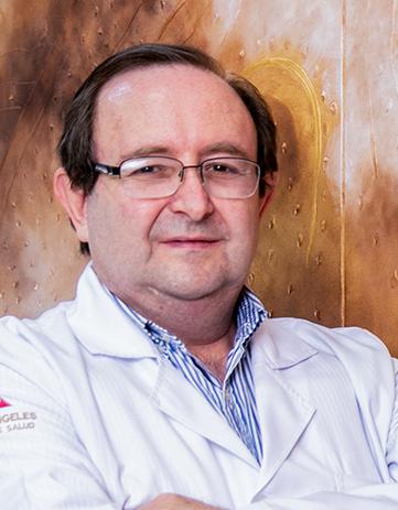 Es la foto de perfil de un cirujano cardiotorácico en León de Hospital Angeles León. Tiene el cabello café oscuro. Usa lentes, una bata blanca y una camisa de cuadros azul con blanco.