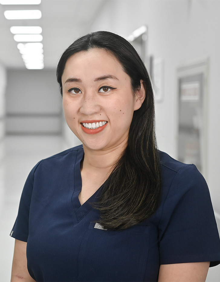 Es la foto de perfil de una ginecóloga y obstetra en Ciudad de México de Hospital Angeles Universidad. Usa un uniforme médico azul. Tiene el cabello largo, lacio y negro. Está sonriendo.