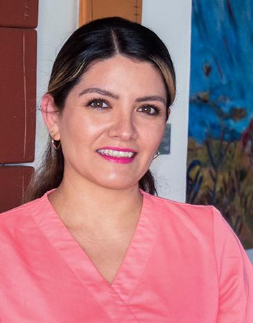 Es la foto de perfil de una otorrinolaringóloga en Xalapa de Hospital Angeles Xalapa. Usa un uniforme médico color rosa. Su cabello es largo, lacio y castaño. Está sonriendo.
