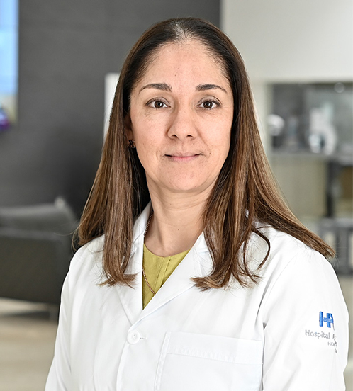 Es la foto de perfil de una ginecóloga y obstetra en San Luis Potosí de Hospital Angeles San Luis Potosí. Usa una bata blanca con un sueter verde limón. Tiene el cabello lacio, largo y castaño. Está sonriendo parcialmete.